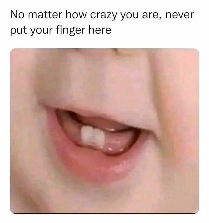 Close-up of a baby's mouth and first tooth with humorous text about not putting a finger there, creating a funny meme.