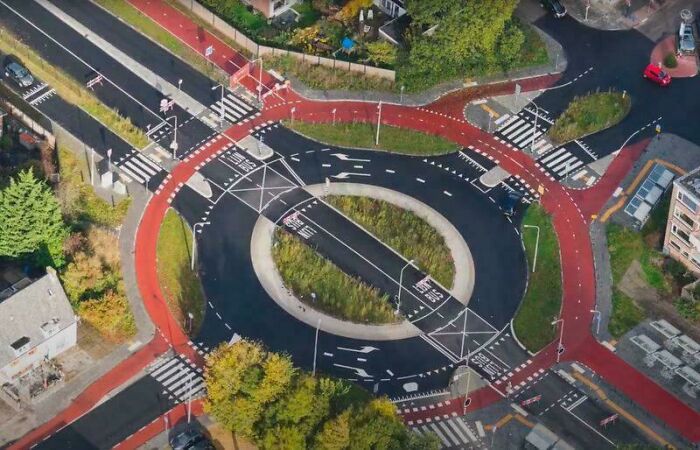 Aerial view of a brilliant infrastructure roundabout featuring bike lanes and pedestrian crossings in an urban setting.