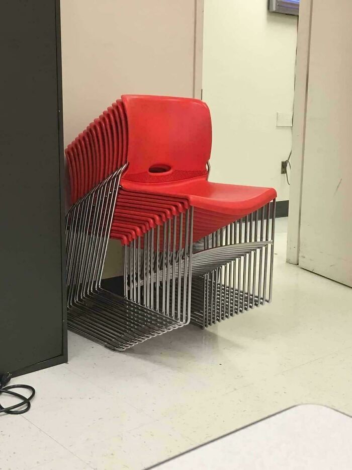 Stacked red chairs in a corner, creating a confusing optical illusion.