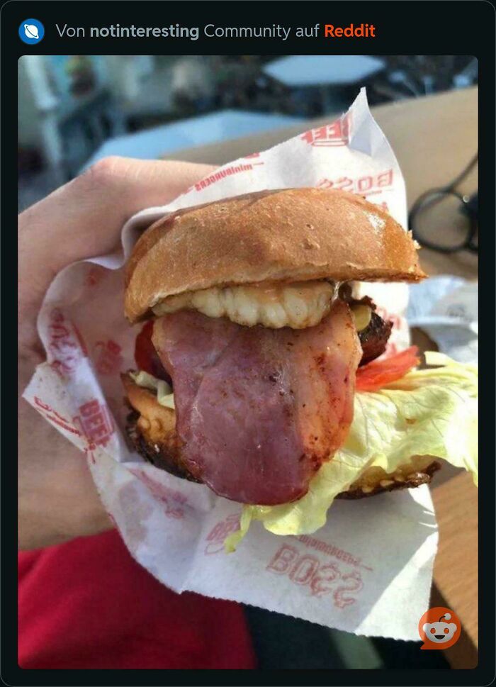 A burger with a large tongue-like bacon slice, creating a confusing visual requiring a double take.