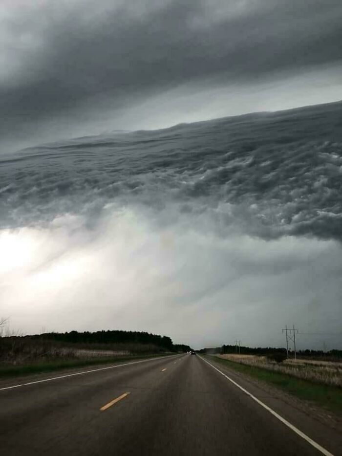 Confusing pic of a road merging with stormy skies creating an optical illusion.