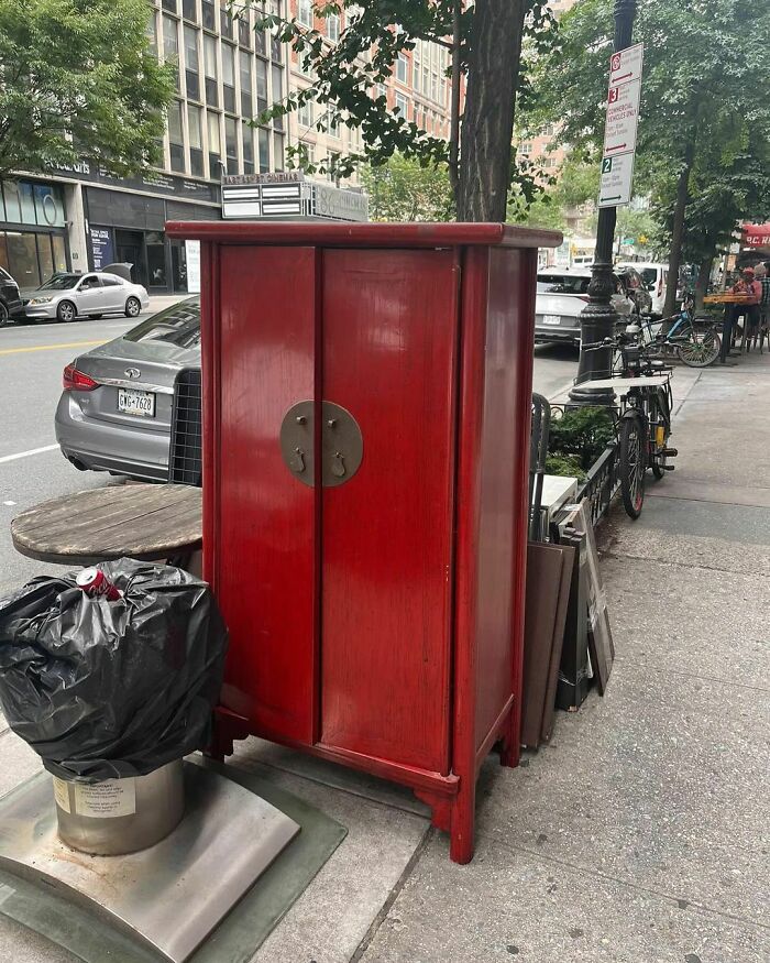 Red cabinet left on a NYC curb, part of the Stooping NYC trend for discovering curbside treasures.