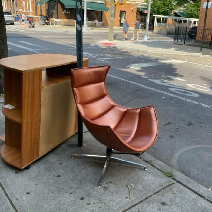 A brown swivel chair and wooden cabinet left on an NYC curb for stooping enthusiasts to find and repurpose.