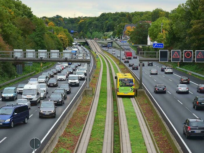 Modern urban infrastructure showing a busy highway with multiple lanes and a dedicated tram track in the center.