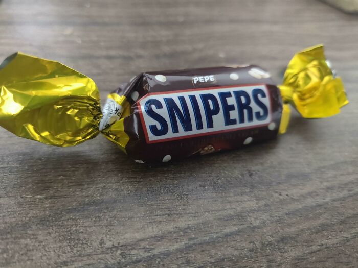 Close-up of a hilarious bad rip-off candy called Snipers, resembling a well-known chocolate brand, wrapped in yellow foil.