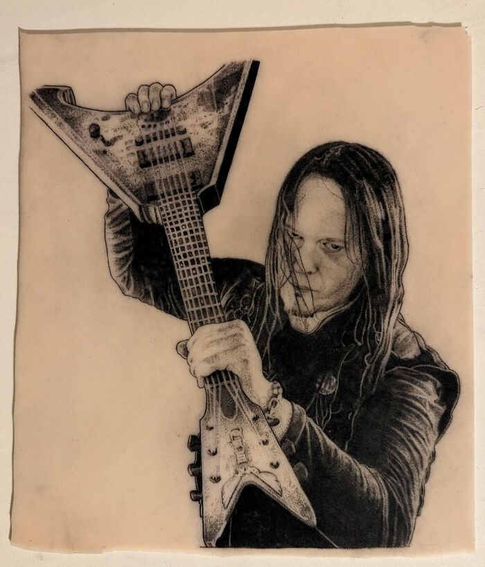 Tattoo artist showcases an intricate design of a musician playing an electric guitar, highlighting exceptional tattoo artistry.