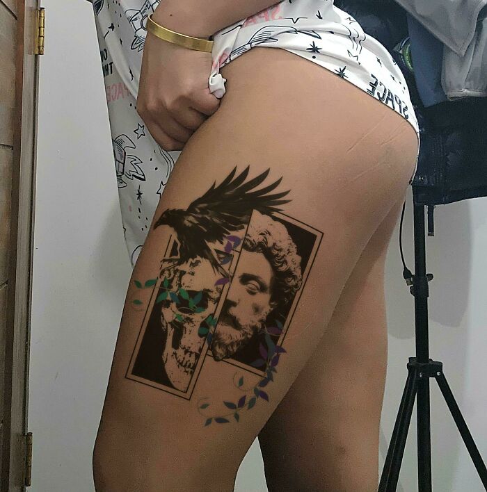 Intricate tattoo design on thigh, featuring a raven and classical bust, showcasing exceptional tattoo artistry and creativity.