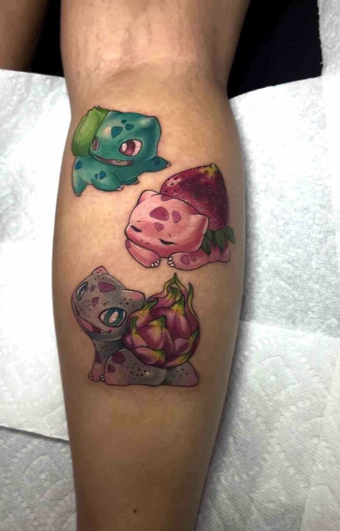 Creative tattoo design featuring vibrant creature illustrations with unique fruit elements on a person's leg.