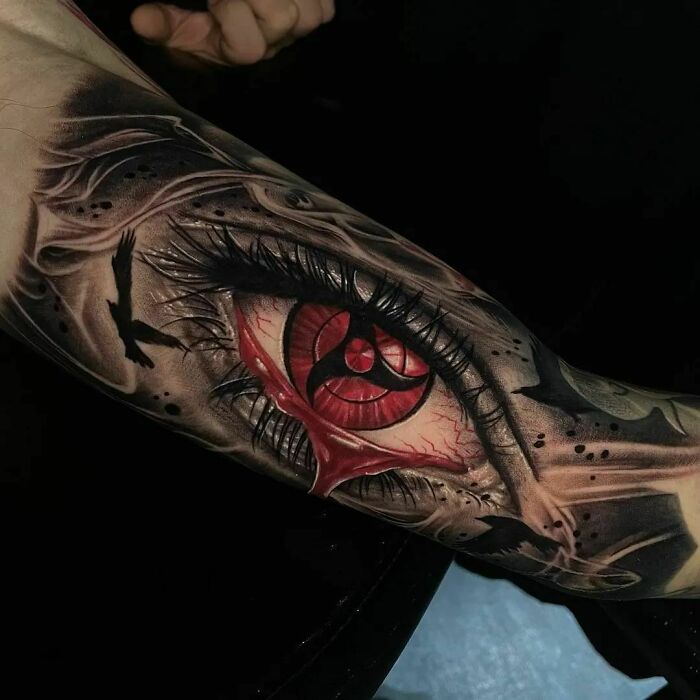 Intricate tattoo design featuring a detailed red eye with birds, showcasing exceptional artistry.