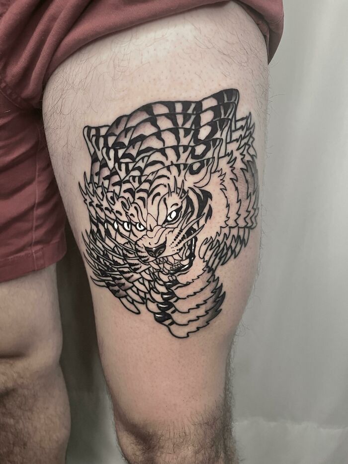 Artistic tiger tattoo design on a person's thigh, showcasing intricate line work by skilled tattoo artists.