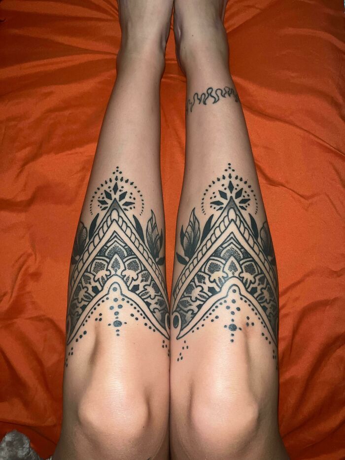 Detailed symmetrical tattoo designs on calves, showcasing intricate artistry.