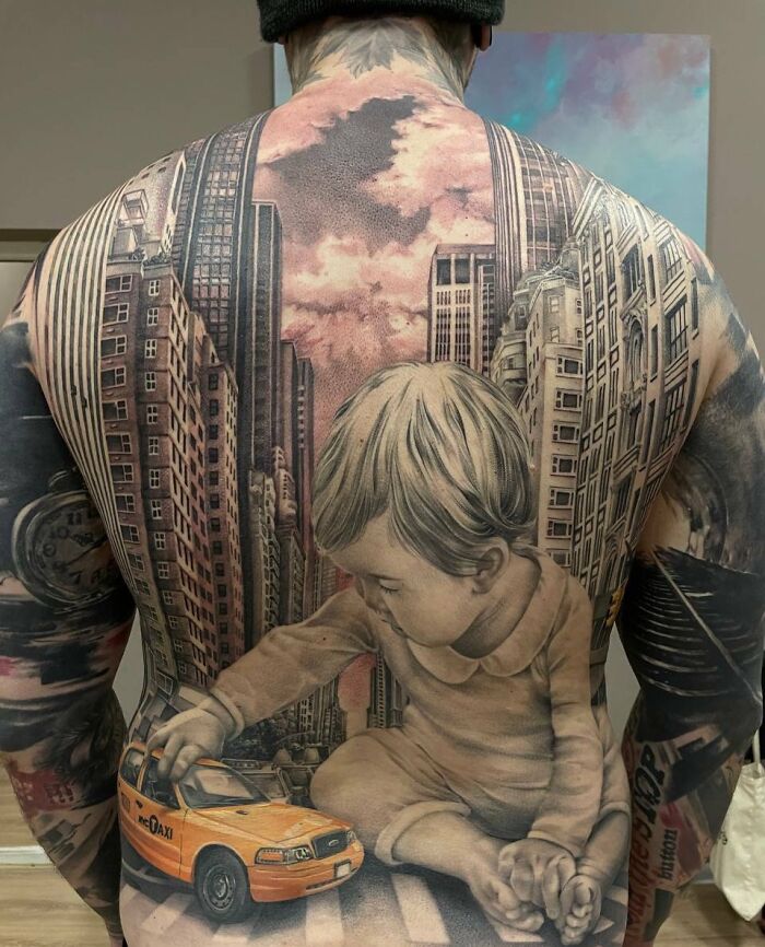 Detailed tattoo covering a back, featuring a cityscape backdrop with a large child playing with a taxi, showcasing tattoo design.