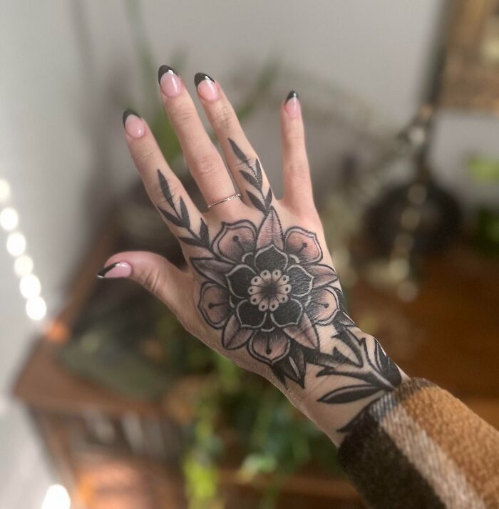 Hand with intricate tattoo design featuring a floral pattern, demonstrating exceptional creativity by tattoo artists.