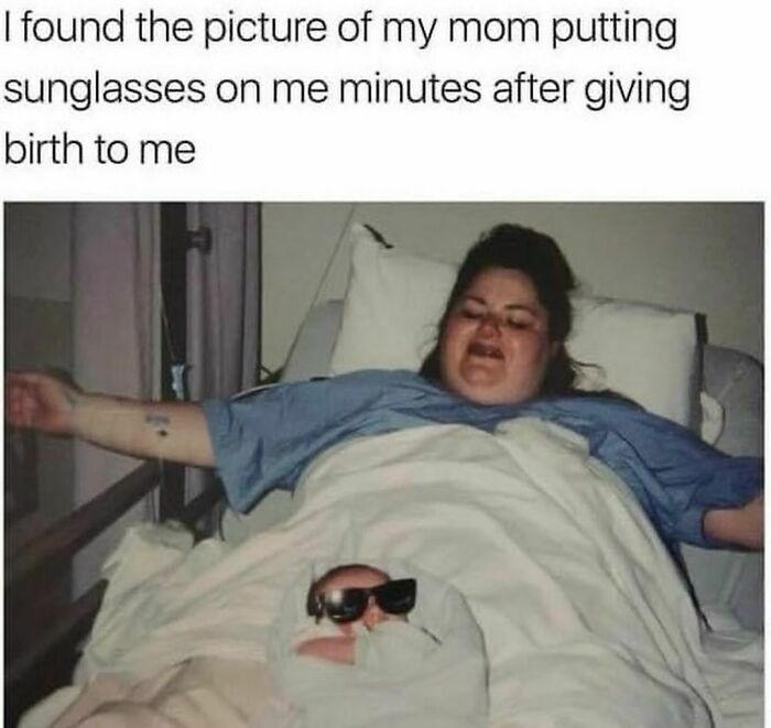 Newborn wearing sunglasses on mother's chest post-birth.