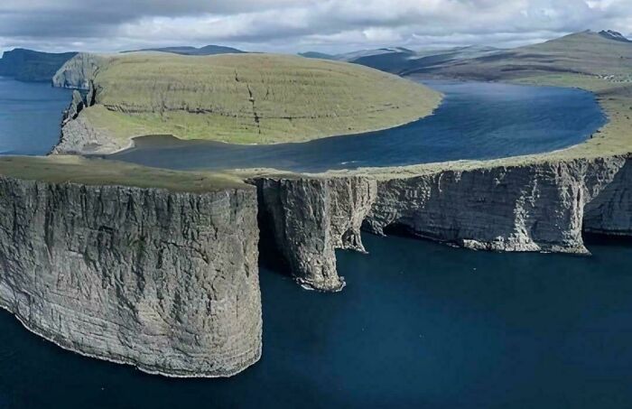 Paisaje sorprendente de la naturaleza con acantilados y agua azul, cielo nublado al fondo.