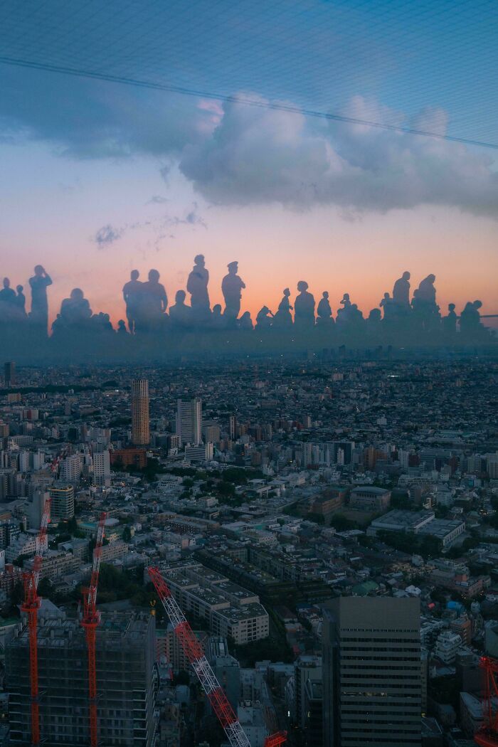 Skyline with sunset reflections creating confusing silhouette illusions in the sky over a city.