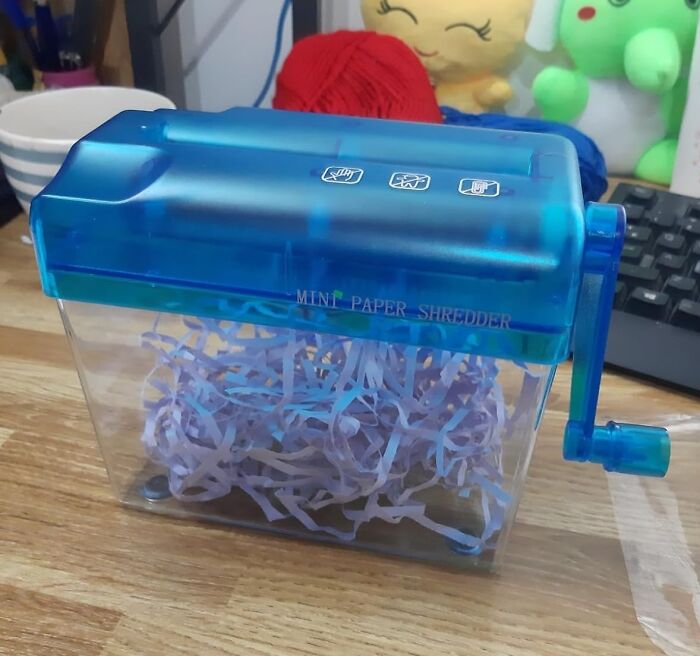 Mini paper shredder on a desk, filled with shredded paper, representing office Olympics fun.