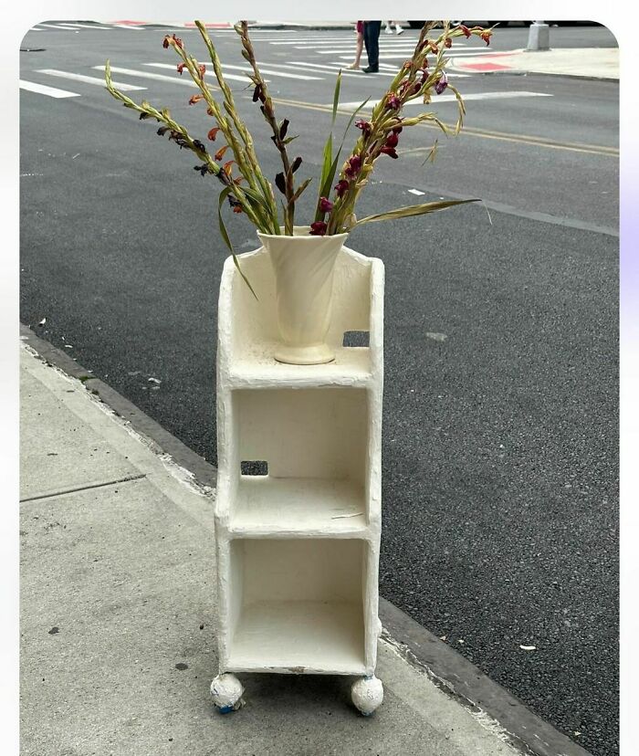 White shelving unit with a vase on top, spotted on the curb in NYC.