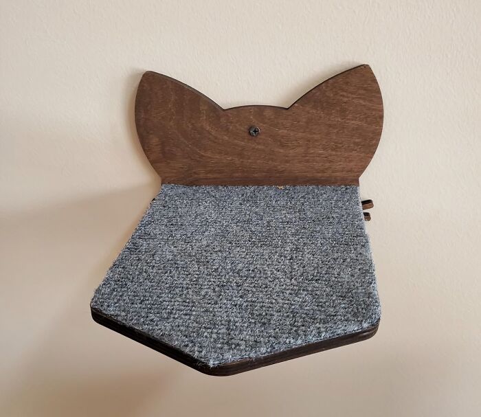 Wooden cat-shaped shelf with gray carpet, wall-mounted, showcasing hidden contractor design secrets.