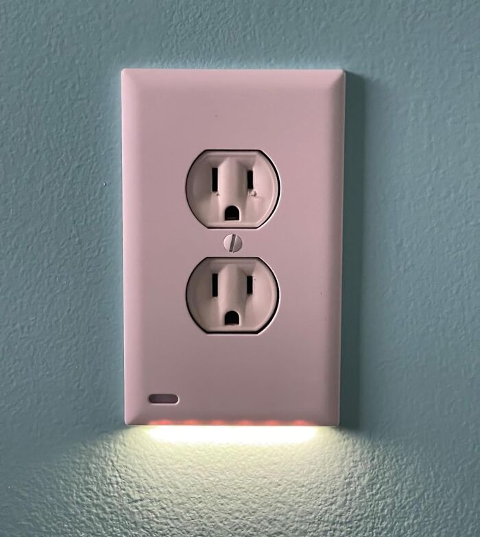 Nightlight outlet with weirdly wonderful find design illuminating a blue wall in a home setting.