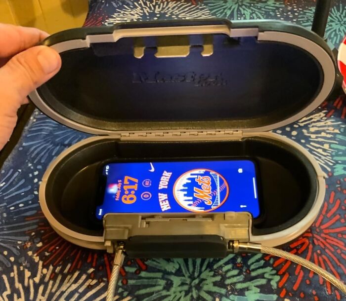 Hand holding open a weirdly wonderful find, showing a phone charging inside a secure black and gray device case.