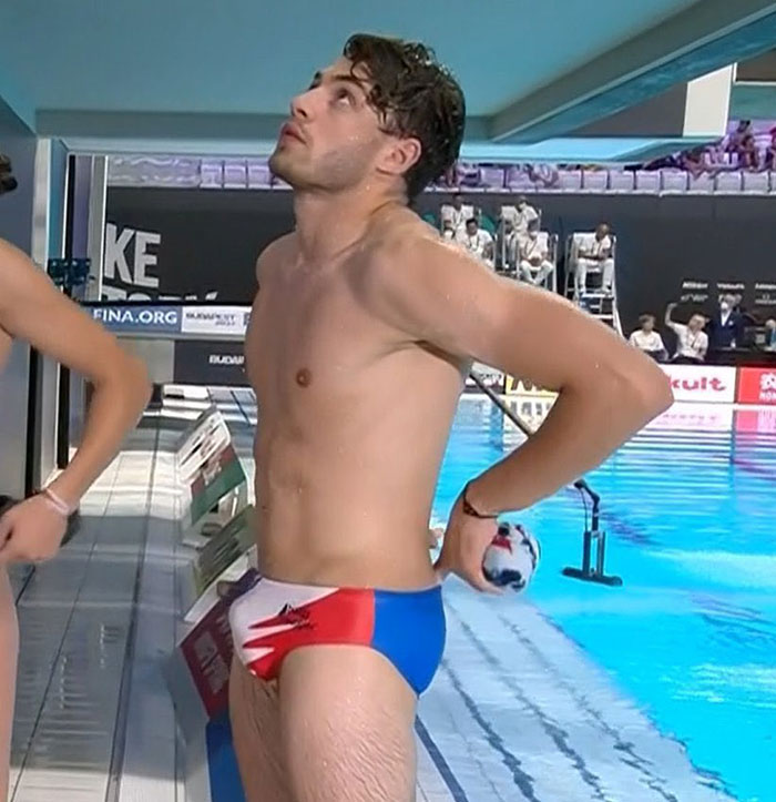 French diver at Olympics poolside, wearing tight swimming trunks, creating buzz.