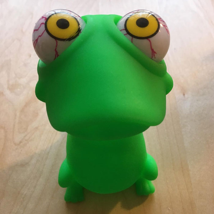 Green dinosaur toy with big bulging eyes, a ridiculous find for your meme adventures.