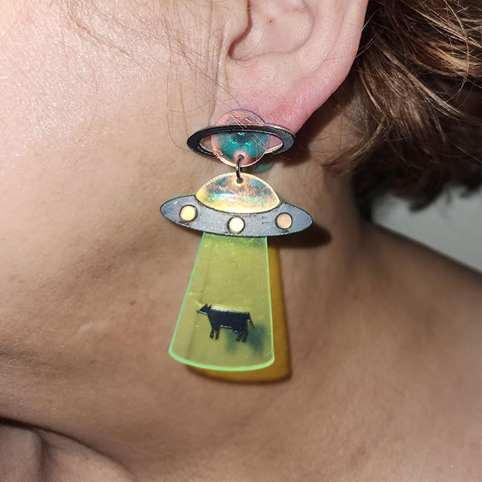 Earring shaped like a UFO beaming up a cow, showcasing a ridiculous find.