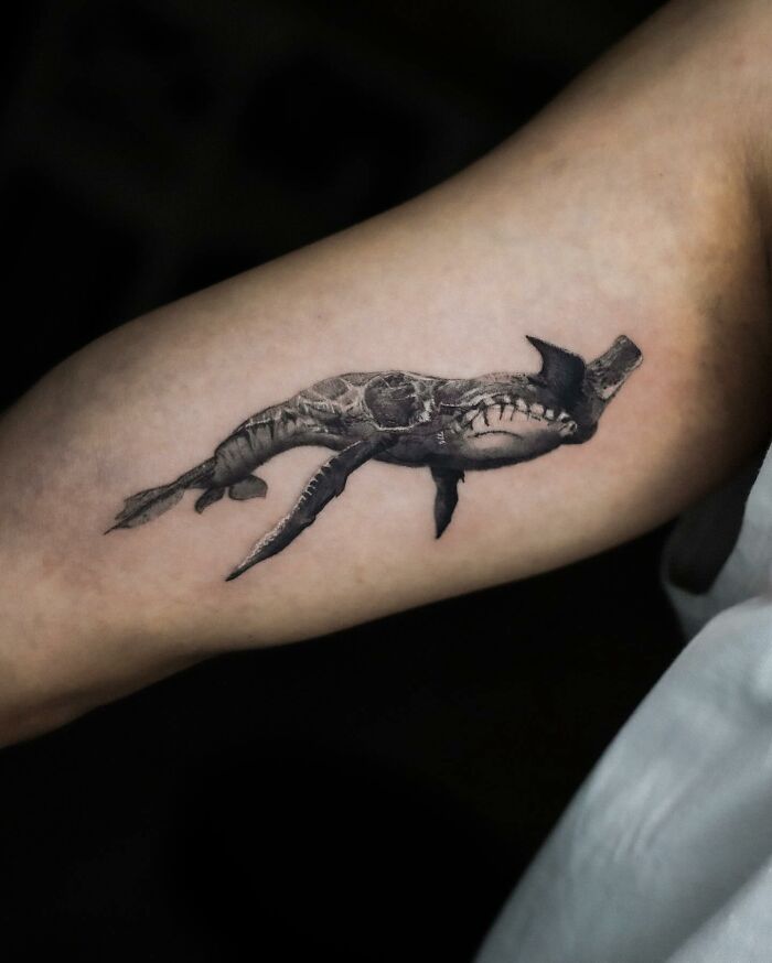Hyperrealistic tattoo of a shark on an arm, showcasing intricate details that resemble a photograph.