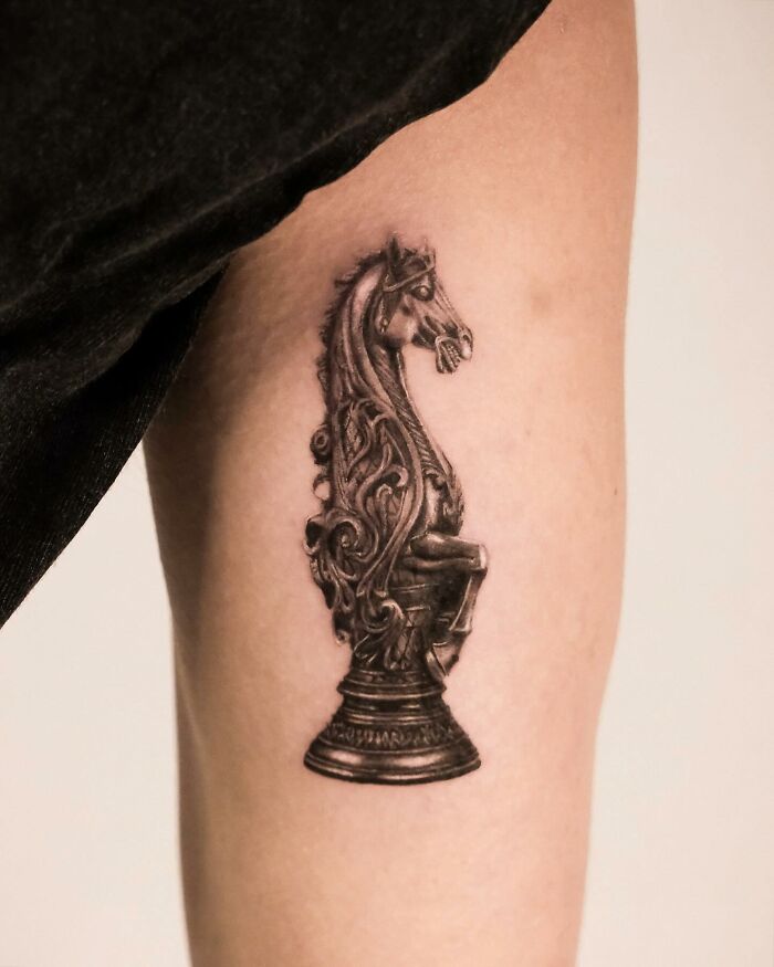 Hyperrealistic horse chess piece tattoo with intricate details on the inner arm.