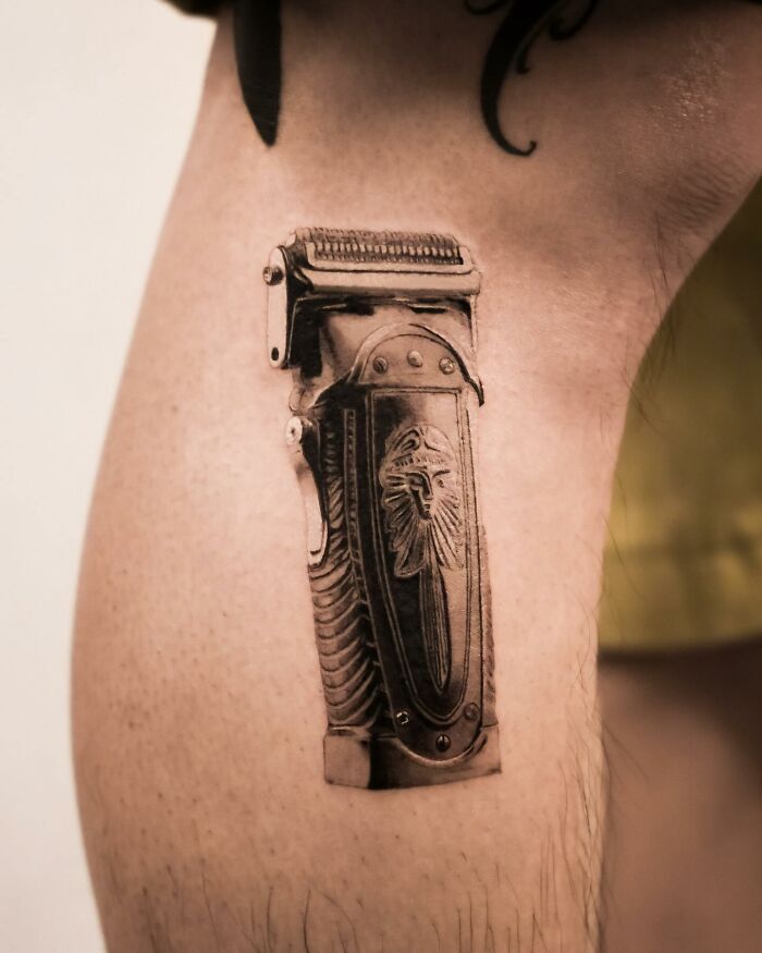 Hyperrealistic tattoo of a vintage hair clipper on a person's leg.