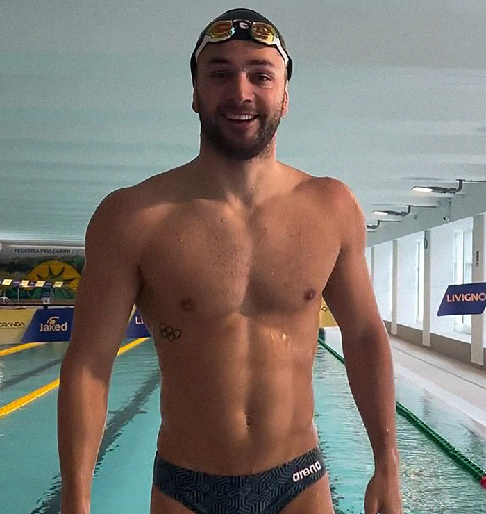 Dutch swimmer at the 2024 Olympics wearing revealing trunks, smiling by the pool.