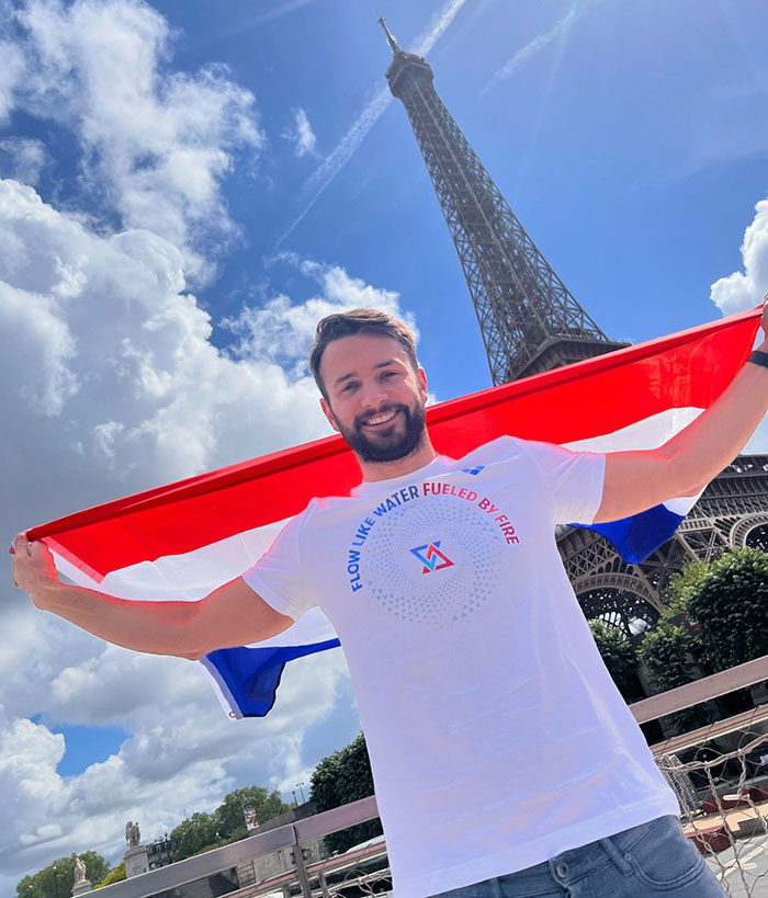 Dutch swimmer with a flag at Eiffel Tower during 2024 Olympics.