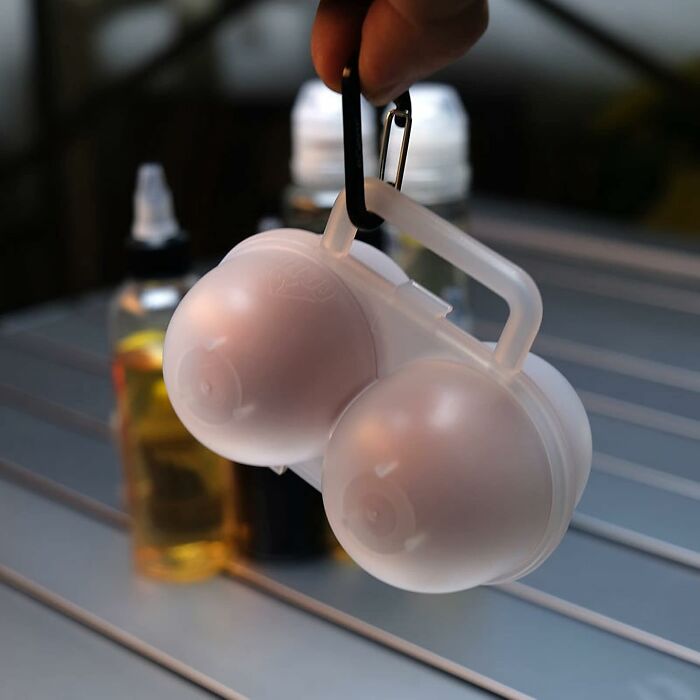 Hand holding a portable egg container with a carabiner, showcasing a clever camping hack for the great outdoors.