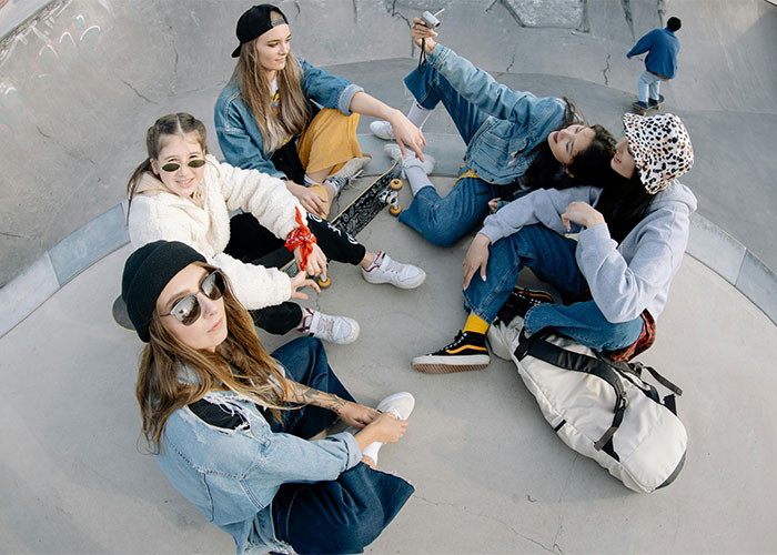 Teens in casual wear sitting in a circle at a skate park, embodying Gen Alpha style and culture.