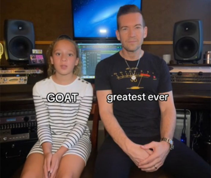 Father learning slang from daughter in a music studio, with text "GOAT" and "greatest ever" on screen.