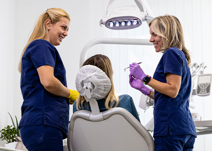 Two dental professionals with a patient in a clinic, discussing treatment options.