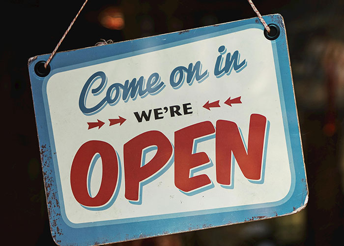 Sign saying come on in we're open, symbolizing work environment and potential colossal mess-ups at work.