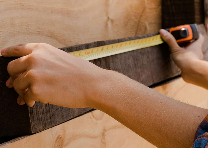 Person measuring wood with tape measure, illustrating one of the most colossal mess-ups people have made at work.