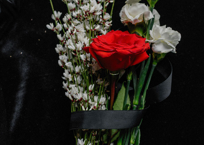 A close-up of a bouquet featuring a red rose and white flowers against a dark background, illustrating work mess-ups.
