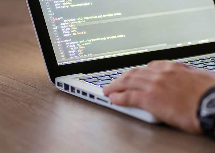 Person working on laptop with visible code, illustrating colossal mess-ups people have made at work in tech settings