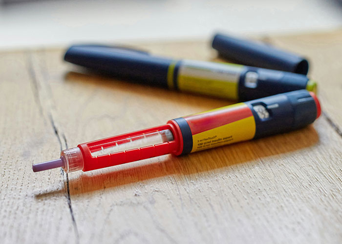 Two insulin pens on a wooden surface representing a colossal mess-up people have made at work involving medical errors.
