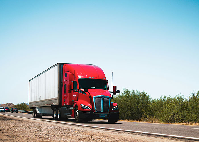 Red semi truck driving on a highway in clear weather, illustrating colossal mess-ups people have made at work.