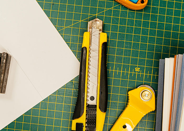 Yellow utility knife and paper cutter on a craft cutting mat, illustrating common colossal mess-ups people have made at work.