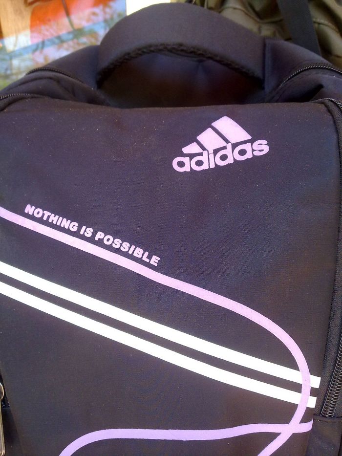Black backpack with a misspelled Adidas logo and altered slogan reading nothing is possible, showcasing a brand rip-off.