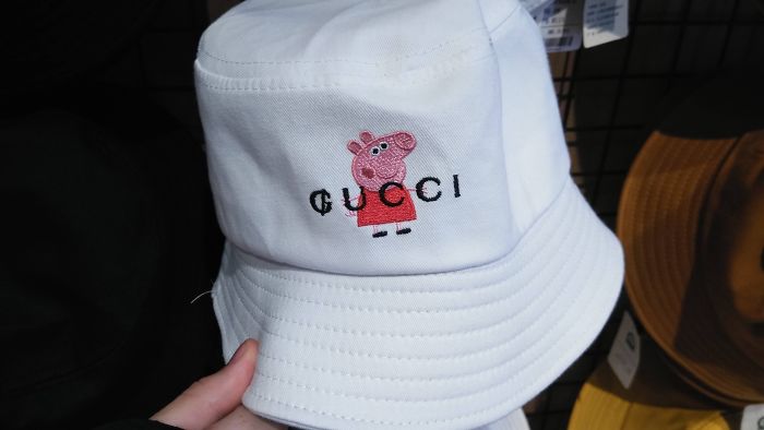 White bucket hat featuring a funny rip-off of Gucci brand with a cartoon character printed on front.