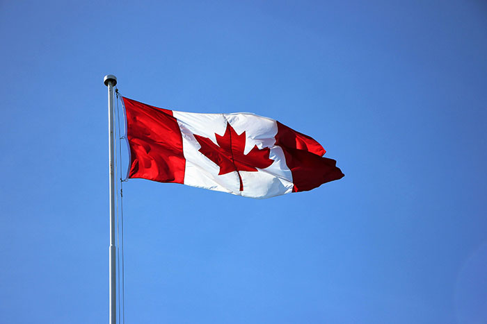 "Canadian flag waving against a clear blue sky, representing historical facts not in textbooks."