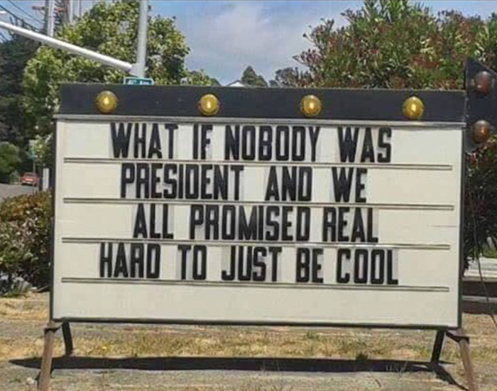 Outdoor sign reads, "What if nobody was president and we all promised real hard to just be cool," capturing relatable humor.
