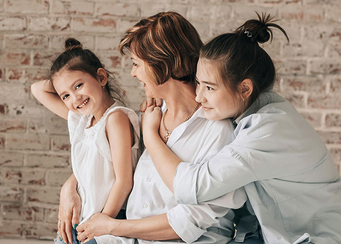 Three women smiling and hugging, symbolizing family bonds and joy. Three women smiling and hugging, symbolizing family bonds and joy.