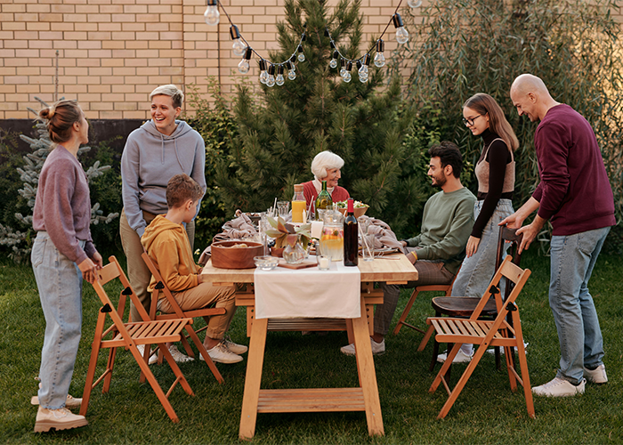 Family gathering outdoors, discussing tattoo and boundaries, around a wooden table with food and drinks. Family gathering outdoors, discussing tattoo and boundaries, around a wooden table with food and drinks.
